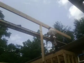 Carpenter setting a ridge beam over a new addition frame in Rural Hall