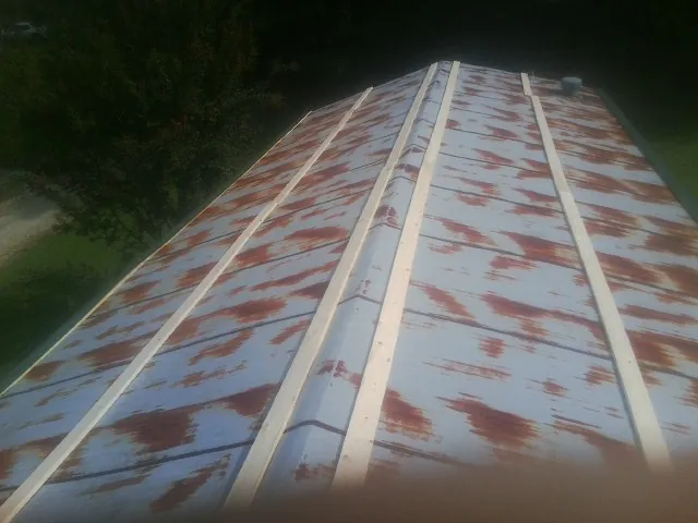 Rusted metal roof panels with new wood purlins before replacement — Storm Damage Roof Repair in Rural Hall by Roofing Brothers