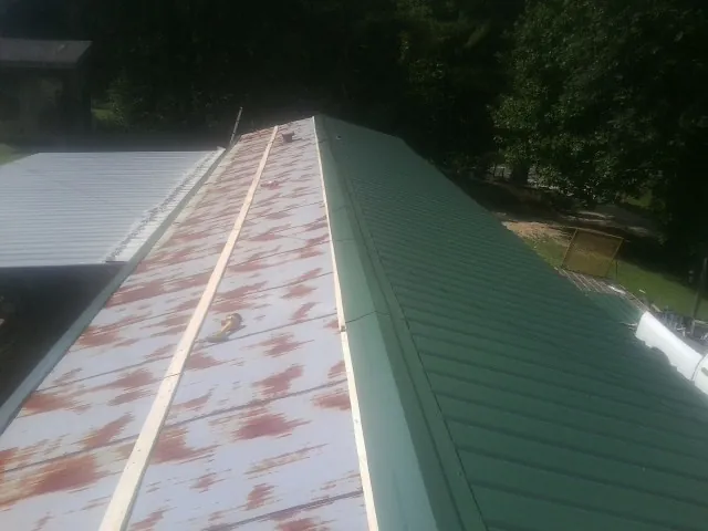 Old rusted panels beside newly installed green metal roofing — Wind Damage Roof Repair by Roofing Brothers in Rural Hall