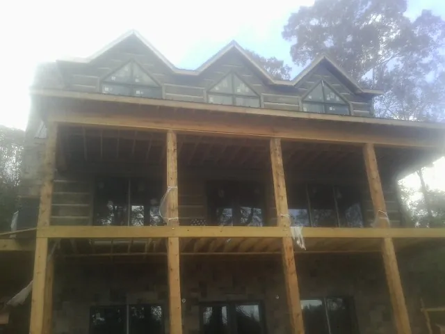 Dormers and porch framing on a large log home under construction — Roof Coating work by our crew in Rural Hall