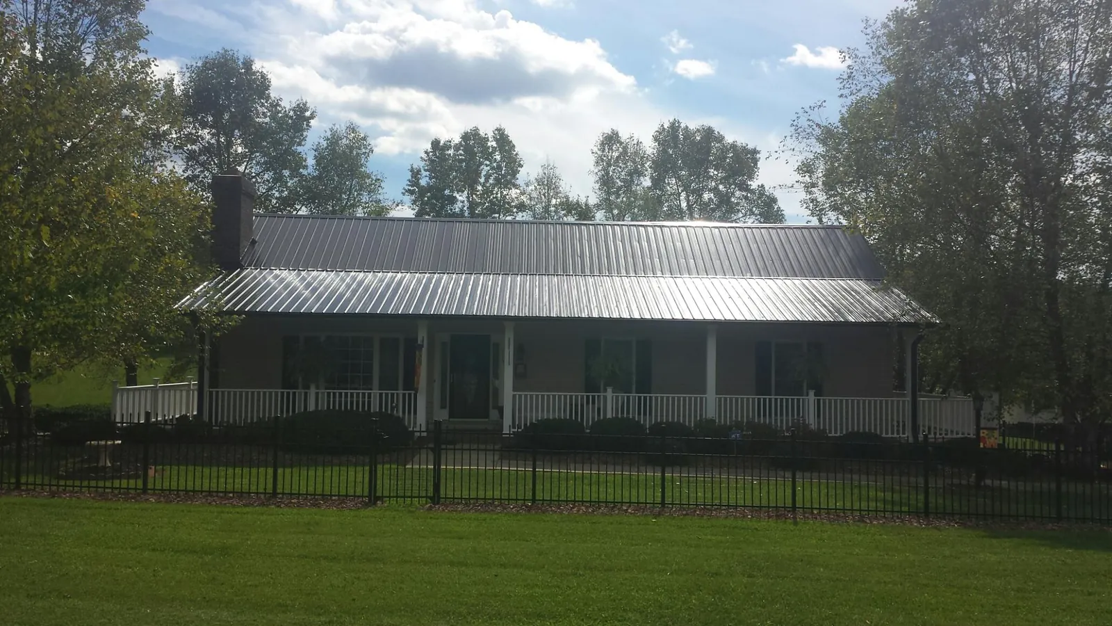 Gray metal roof on a brick ranch with a full width front porch — Gutter Guard Installation work by our crew in Rural Hall