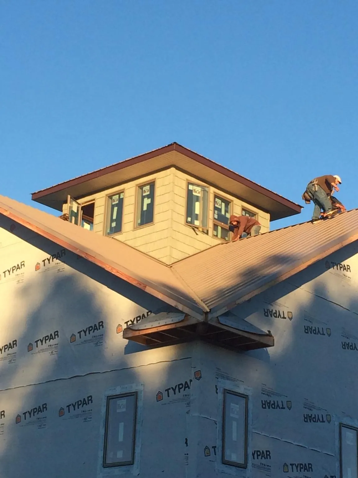 Roofers working around a rooftop cupola on a new metal roof at sunset — Roof Waterproofing in Rural Hall by Roofing Brothers